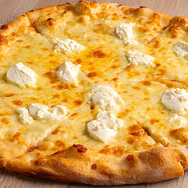 Close-up of a sliced white pizza with melted cheese and dollops of ricotta on a wooden surface.