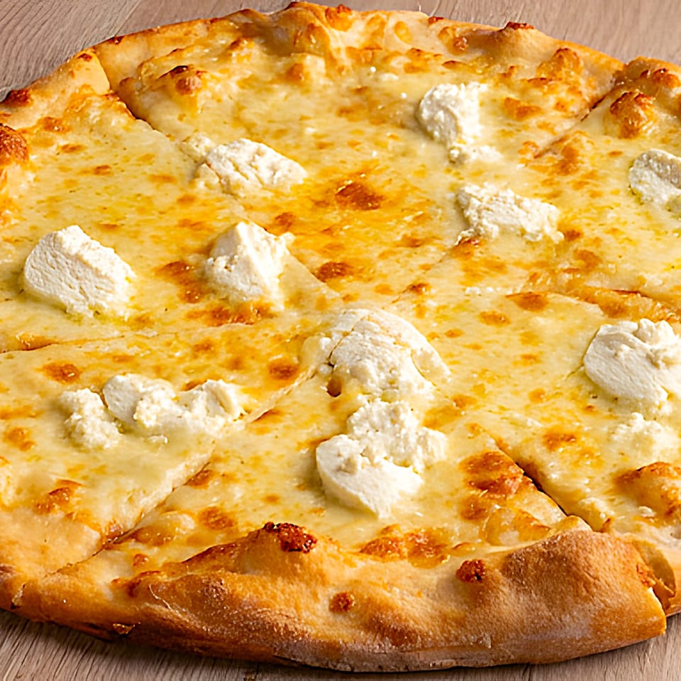 Close-up of a sliced white pizza with melted cheese and dollops of ricotta on a wooden surface.